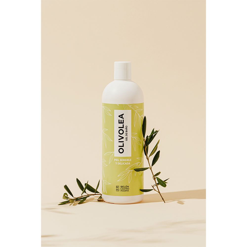 Envase de gel de baño Olivolea para piel sensible en color verde claro, acompañado de rama de olivo, fondo beige