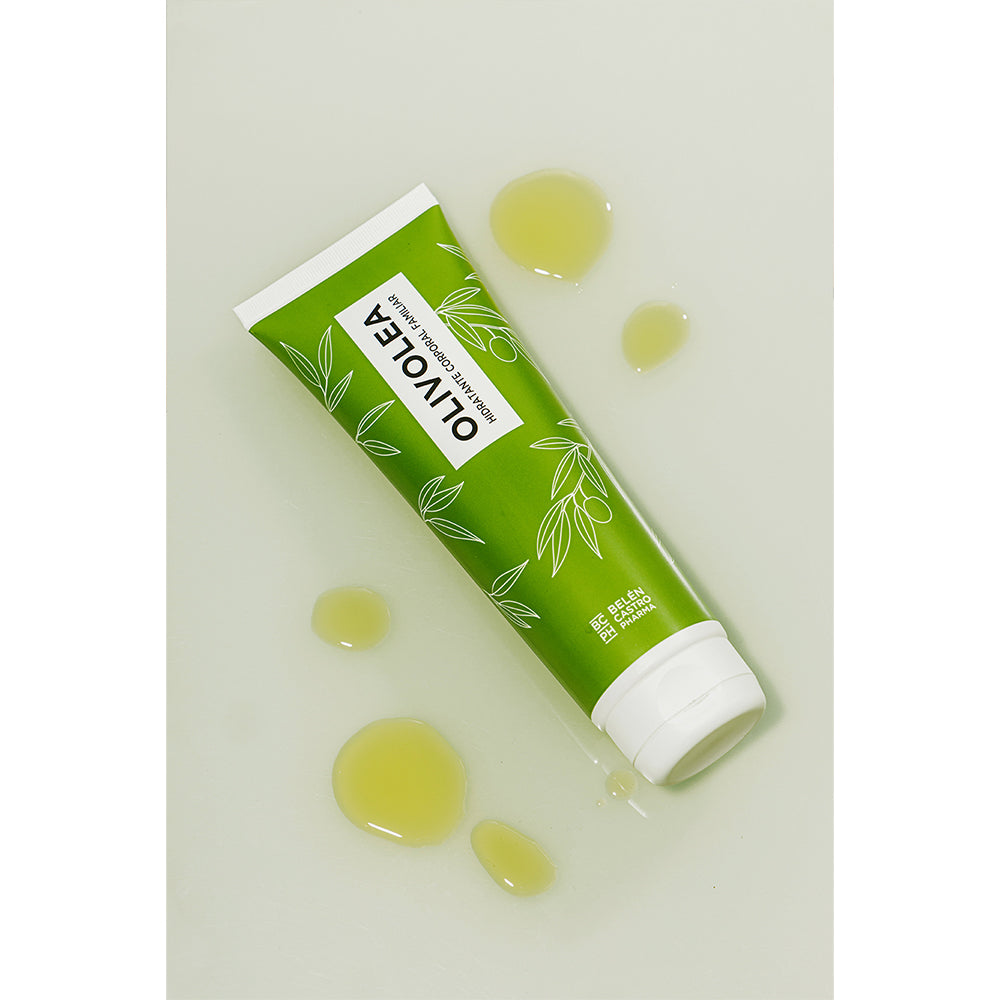 Envase de crema Olivolea hidratante corporal familiar en color verde rodeado de gotas de producto sobre superficie clara.