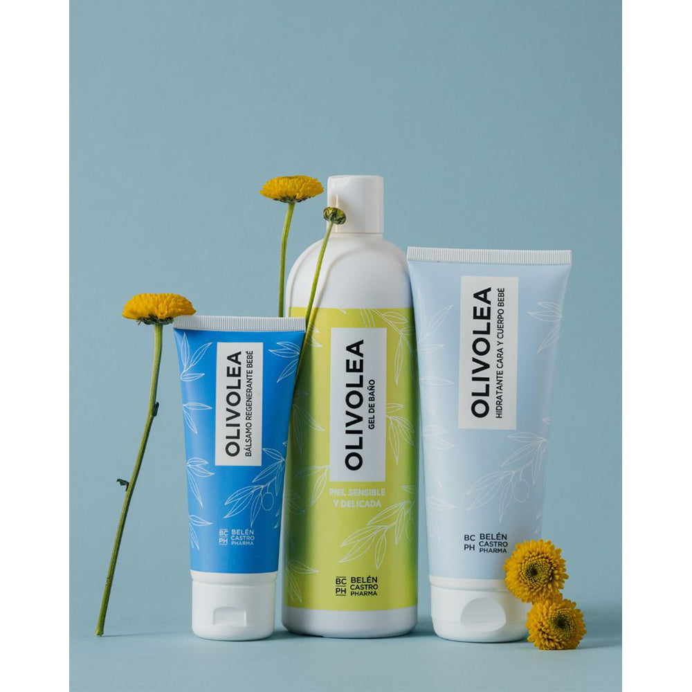 Productos Olivolea: bálsamo, gel de baño e hidratante en envases azul y verde, decorados con flores amarillas, fondo azul.